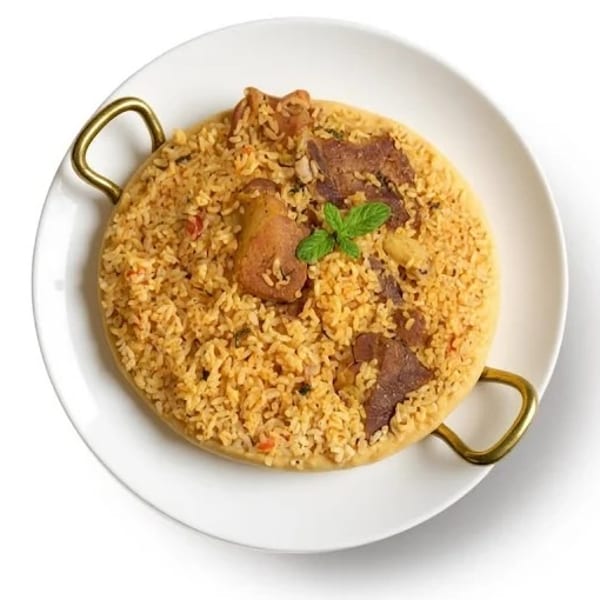 A round, golden biryani dish with meat and a mint garnish, served on a white plate.