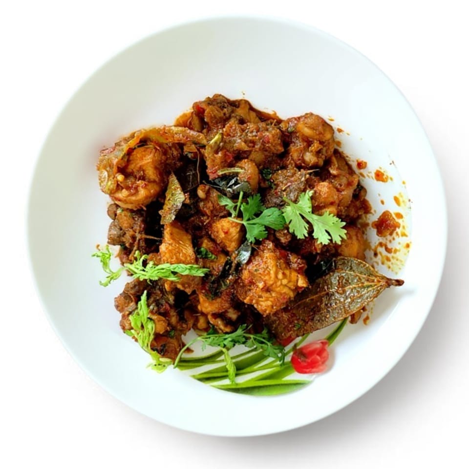 Spicy chicken curry with cilantro and bay leaves on a white plate.