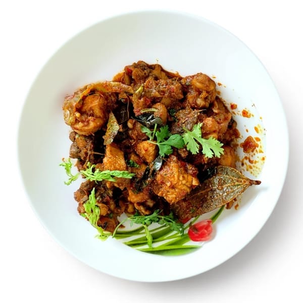 Spicy chicken curry with cilantro and bay leaf garnish on a white plate.