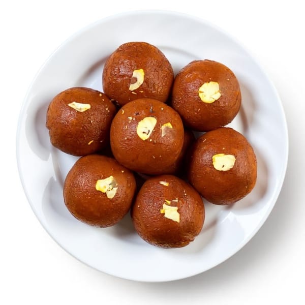 Seven brown gulab jamun, garnished with slivered almonds, arranged on a white plate.